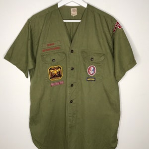 May include: Green short-sleeved button-up shirt with various scout patches, including a "Senior National Jamboree" patch, a "Howell Scout Reservation" patch, and a "Crusader Plus" patch.