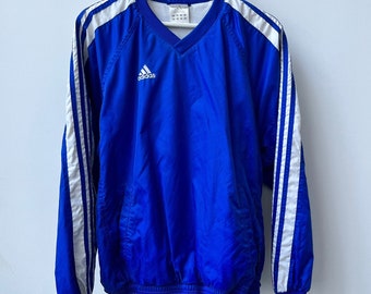 Treningowy top Adidas z lat 90. z tkanym dekoltem w serek i bocznym zamkiem błyskawicznym. Rozmiar XS. Wyprodukowano na Filipinach. Reflex Blue i White. Kultowe trzy paski.