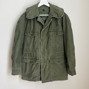 May include: A green military-style jacket with a large collar, four flap pockets, and a button closure.