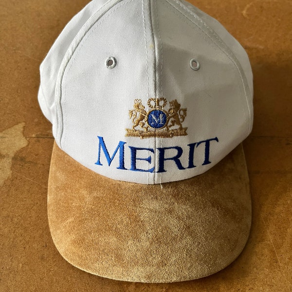 chapeau promotionnel Merit vintage des années 1990. Taille unique Snap back. Bec en daim avec coton. Blanc, beige, or et bleu Klein. Brodé devant et dos.