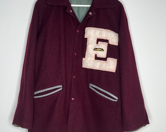 Vintage wollen zijjack uit de jaren 50-60 met raglanmouwen en zwempatch van chenille 'E'. Bordeauxrood met grijze leren details. Gelabeld 42