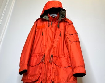 Rzadka zabytkowa kanadyjska parka SAR Tech w kolorze Rescue Orange. Rozmiar 70/40. Pełna detali projektowych. Można ją złożyć i utworzyć torbę z paskami.