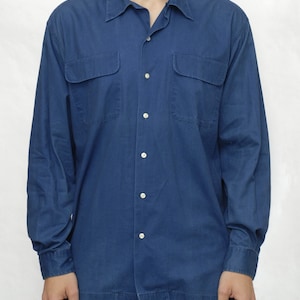 May include: A long-sleeved, blue button-down shirt with two large pockets on the chest.