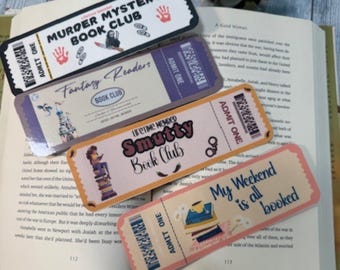 May include: Four colorful bookmarks with a ticket design. The bookmarks feature different book club themes, including "Murder Mystery Book Club", "Fantasy Readers Book Club", "Lifetime Member Smutty Book Club", and "My Weekend is all booked".