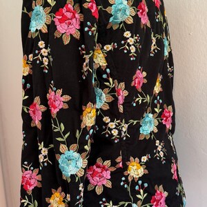 May include: Black jacket with colorful floral embroidery. The jacket features a pattern of pink, red, yellow, and blue flowers with green leaves. The embroidery is detailed and covers the entire jacket.