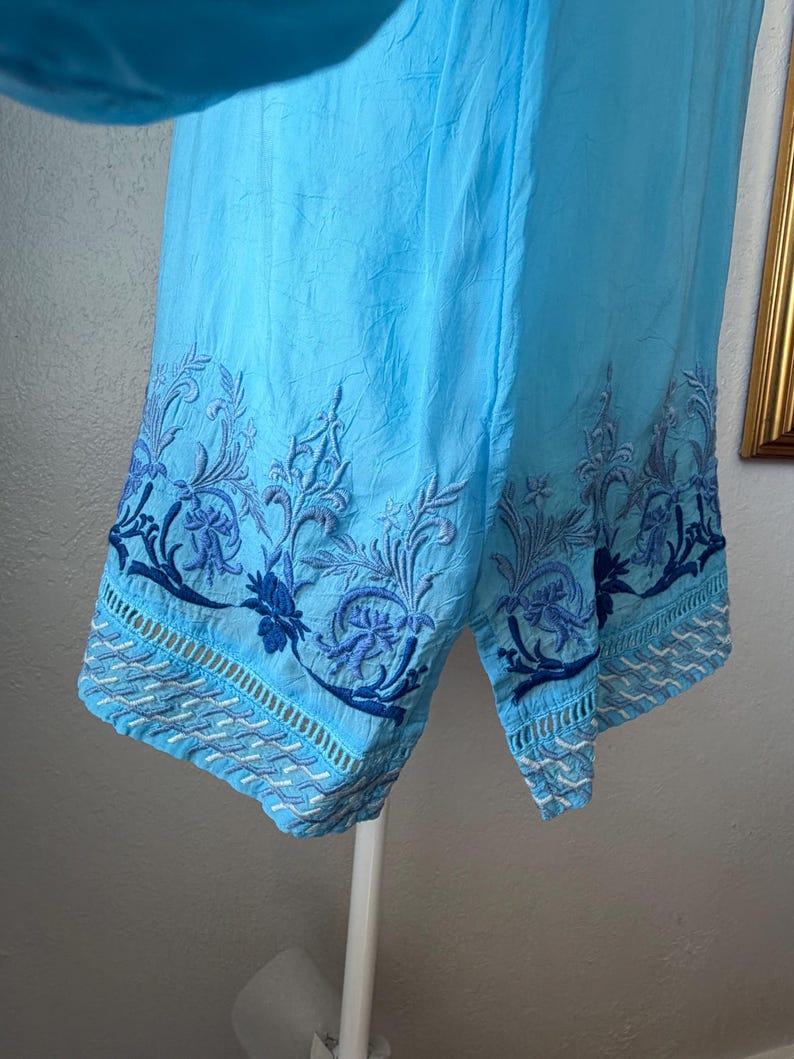 Puede incluir: Shorts de color azul claro con intrincados bordados florales en azul oscuro a lo largo del dobladillo. Los shorts est&aacute;n hechos de una tela ligera. El bordado presenta patrones detallados de flores y hojas. Corte relajado.