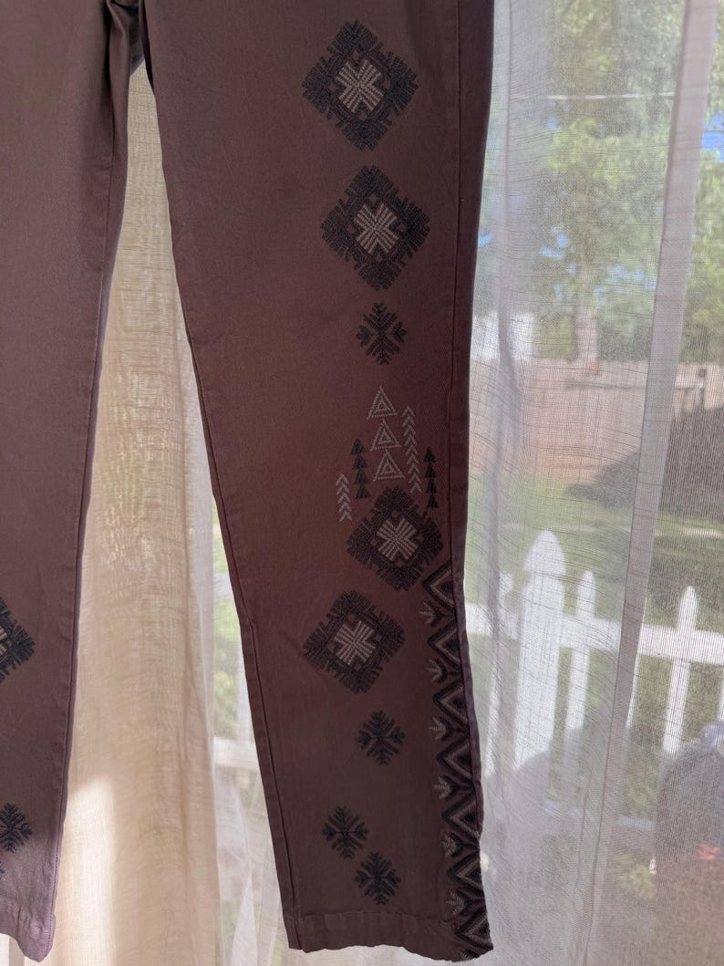 May include: A white ceramic mug with a black handle and the text "But First, Coffee" in a handwritten style. The mug is on a white surface. The mug is approximately 10 cm tall.