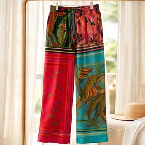 Puede incluir: Pantalones anchos y coloridos con estampado floral tropical. Los pantalones tienen cintura con cord&oacute;n y un dise&ntilde;o de patchwork con tonos vibrantes de rojo, rosa, turquesa y verde. La tela parece ligera y adecuada para el verano.