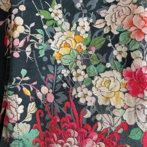 Puede incluir: Una tela negra con un estampado floral denso y multicolor. El patr&oacute;n incluye flores grandes y detalladas en tonos rojo, amarillo, crema y rosa suave, intercaladas con hojas verdes y tallos delicados sobre el fondo oscuro.