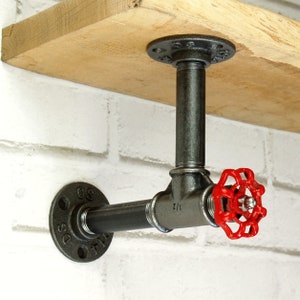 Peut inclure: Un support d'étagère en métal noir avec un robinet industriel rouge. Le support est fixé à une étagère en bois et à un mur de briques blanches. Le robinet est marqué "2 1/2".