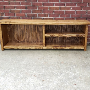 May include: A wooden bench with two shelves, one on each side. The bench is stained a dark brown color and has a rustic look.