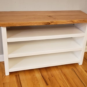 May include: White wooden shoe rack with three shelves and a natural wood top.