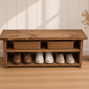 May include: A rectangular wooden shoe bench with a dark brown stained finish, featuring a flat top surface, one middle shelf holding two woven wicker baskets, and a bottom shelf containing three pairs of shoes in brown, white, and beige.