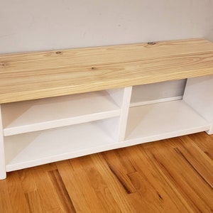 May include: White wooden bench with two shelves for storage. The top of the bench is made of natural wood.