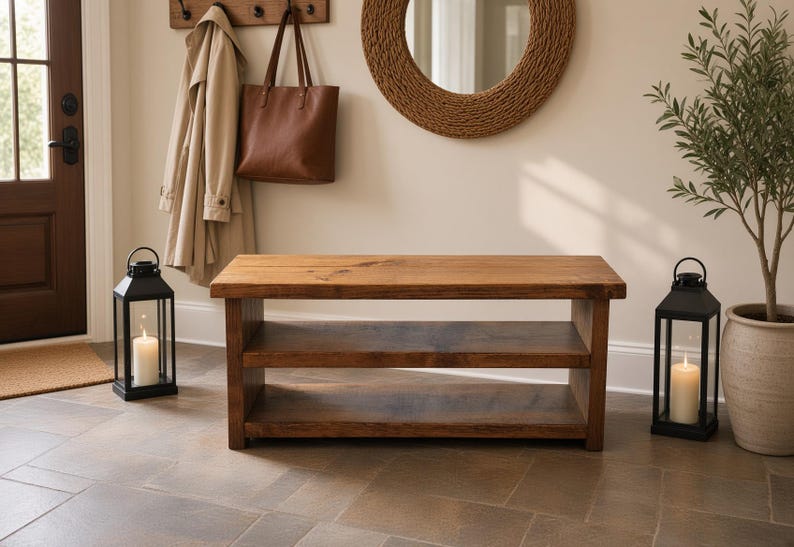 May include: A rectangular wooden bench featuring a natural brown finish with a smooth top surface and a single open shelf underneath, constructed with thick, sturdy planks and visible wood grain patterns throughout the entire furniture piece.
