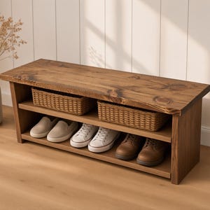 May include: A rectangular wooden shoe bench with a dark brown stained finish. The unit features a flat top surface, an open middle shelf holding two woven wicker baskets, and a bottom shelf containing three pairs of shoes in beige, white, and brown.