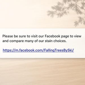 May include: A rectangular white sign with black text that reads: Please be sure to visit our Facebook page to view and compare many of our stain choices. The sign also includes the blue URL: https://m.facebook.com/FallingTreesBySki/