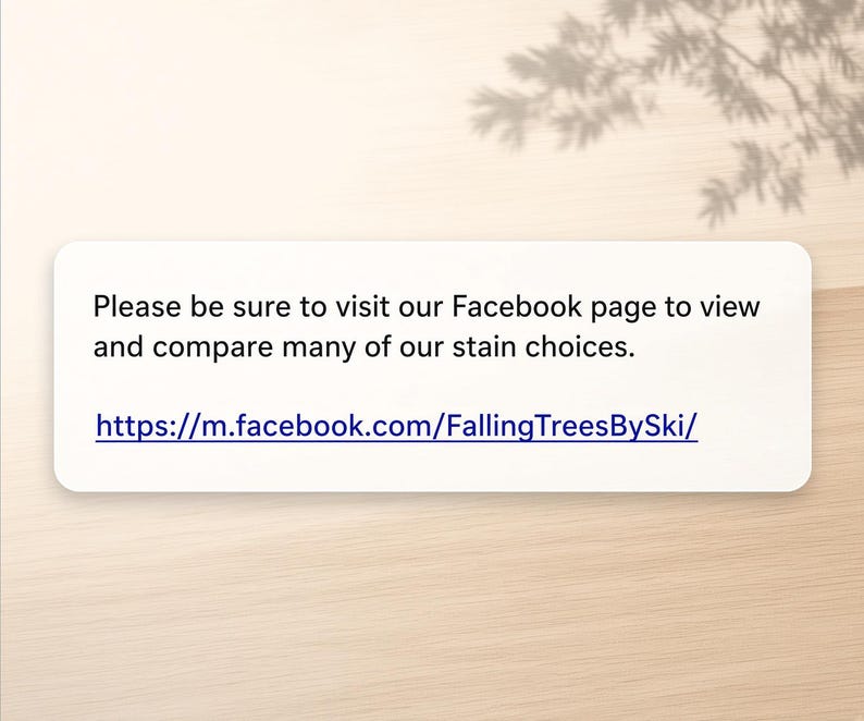 May include: A rectangular white sign with black text that reads: Please be sure to visit our Facebook page to view and compare many of our stain choices. The sign also includes the blue URL: https://m.facebook.com/FallingTreesBySki/