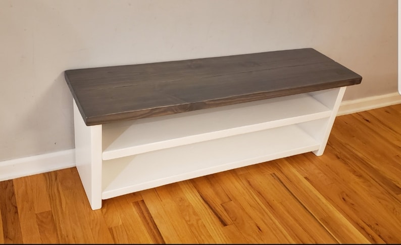 May include: A white wooden bench with a gray stained top and two shelves. The bench is made of wood and has a simple design.