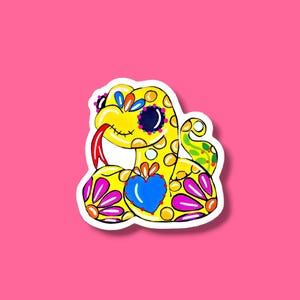 May include: A colorful sticker featuring a stylized snake with a yellow body, adorned with blue, pink, and orange floral patterns. The snake has a red tongue, a blue heart, and a smiling face. The sticker is set against a bright pink background.