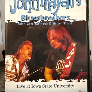 May include: DVD case for John Mayall's Bluesbreakers, featuring Coco Montoya and Walter Trout. The cover has a blue and black background with the band's name in large, stylized letters. The bottom reads "Live at Iowa State University."