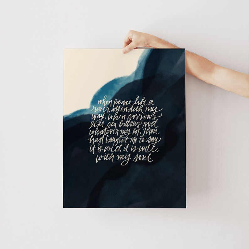 May include: A rectangular art print featuring a dark navy blue watercolor wash background with white cursive text that reads: When peace like a river, attendeth my way, when sorrows like sea billows roll; whatever my lot, Thou hast taught me to say, it is well, it is well, with my soul.