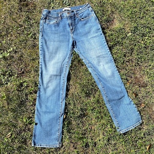 May include: A pair of blue denim jeans with a straight leg fit. The jeans have a classic five-pocket style and a button fly.