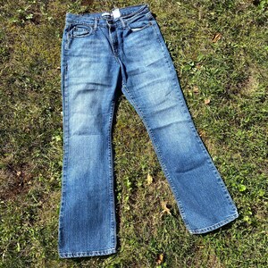 May include: A pair of blue denim jeans with a bootcut style. The jeans have a light wash and are made of a soft, comfortable fabric.