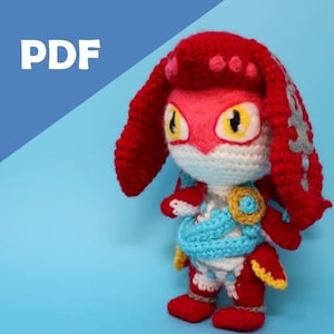 May include: A crocheted plush toy of a red and white character with a red and gray head, blue and white clothing, and yellow eyes. The toy is standing on a blue surface.