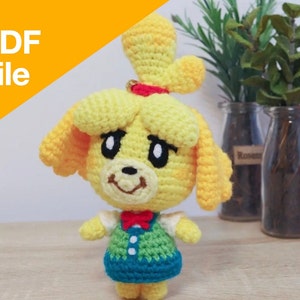 Peut inclure: Patron de crochet PDF pour un personnage de chien jaune avec un nœud papillon rouge, un gilet vert et une jupe bleue. Le personnage a une queue de cheval jaune et des yeux noirs.
