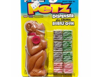 May include: A brown plastic "Grinz" the monkey Pez dispenser with a red button on its chest. The dispenser comes with a pack of Amurol bubble gum in assorted flavors: fruit, grape, and watermelon.