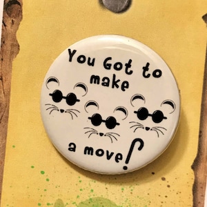 May include: A white button with three cartoon mice wearing sunglasses and the text "You Got to make a move!"  The button is on a yellow background with the quote "What makes us special, makes us strong. -Shrek"