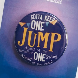 May include: A blue and yellow button with the text "Gotta Keep One Jump Ahead of the Breadline One Swing Ahead of the Sword" from the musical Aladdin.