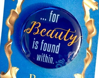 May include: A blue and gold button with the quote "...for Beauty is found within."  The button is surrounded by a gold frame and the words "Beauty and the Beast" are printed below the button.