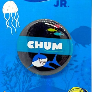 May include: A blue and white button with a cartoon shark and the word "CHUM" on it. The button is on a blue background with a jellyfish, starfish, and fish. The text "FINDING NEMO JR." is at the top of the card.