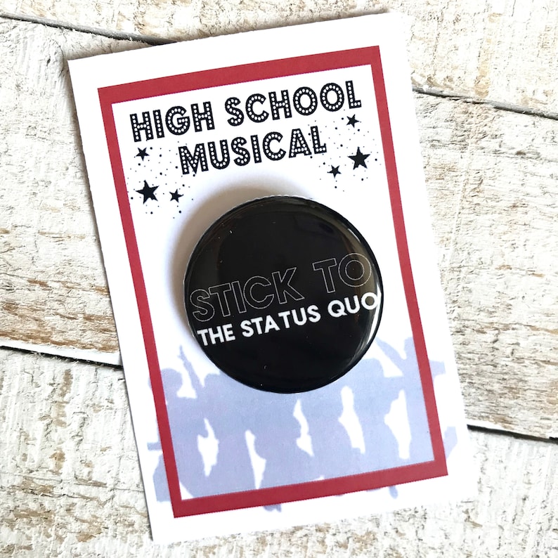 以下が含まれることがあります： 白い文字で「Stick to the Status Quo」と書かれた黒いボタン。赤い星と白い星が散りばめられた赤と白の背景に「High School Musical」と書かれている。