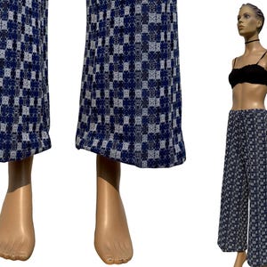 Op de afbeelding: Broek met wijde pijpen met een blauw en wit geruit patroon. De broek wordt getoond op een mannequin, waarbij het ontwerp van de stof wordt getoond. De broek heeft een hoge taille en een losse pasvorm, geschikt voor casual wear.