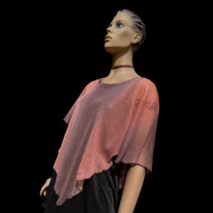 Peut inclure: Un haut en tricot dégradé rose et violet à la coupe ample et fluide. Le haut a un col rond et des manches courtes.