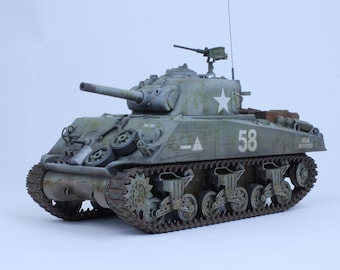 May include: A green and gray model of a Sherman tank with a white star and the number 58 on the side. The tank has a machine gun on top and is on a white background.