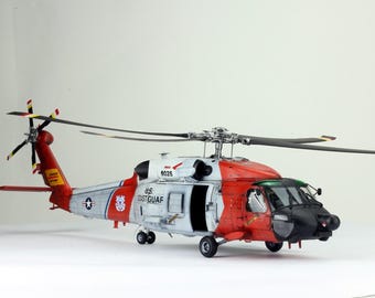May include: A white, red, and black Coast Guard helicopter model with the text "US Coast Guard" and "8028" on the side. The helicopter has a black rotor and a clear cockpit.