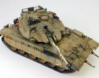 May include: A detailed model of a military tank with a green camouflage paint scheme. The tank has a large turret with a main gun and several smaller guns. The tank is on a white background.