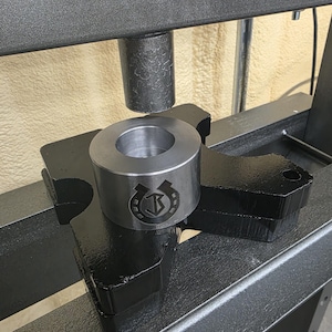 May include: A white ceramic mug with a black handle and the text "But First, Coffee" in a bold, black font. The mug is set against a blurred background, suggesting a cozy setting.