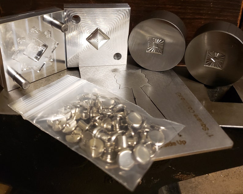 Puede incluir: Una colecci&oacute;n de herramientas y hardware de metal. La imagen muestra varios sellos met&aacute;licos cuadrados y circulares con dise&ntilde;os geom&eacute;tricos detallados, junto con una bolsa de pl&aacute;stico transparente llena de peque&ntilde;os sujetadores met&aacute;licos. Tambi&eacute;n es visible una plantilla de metal.