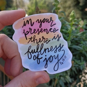 May include: A sticker with a watercolor background in shades of orange, yellow, green, and blue. The sticker features the text "in your presence there is fullness of joy" with the scripture reference "Ps 16:11" in smaller font.