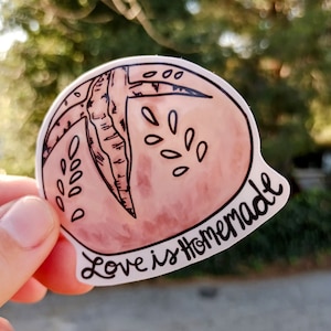 May include: A pink and white sticker with a hand-drawn illustration of a peach and the text "Love is Homemade".