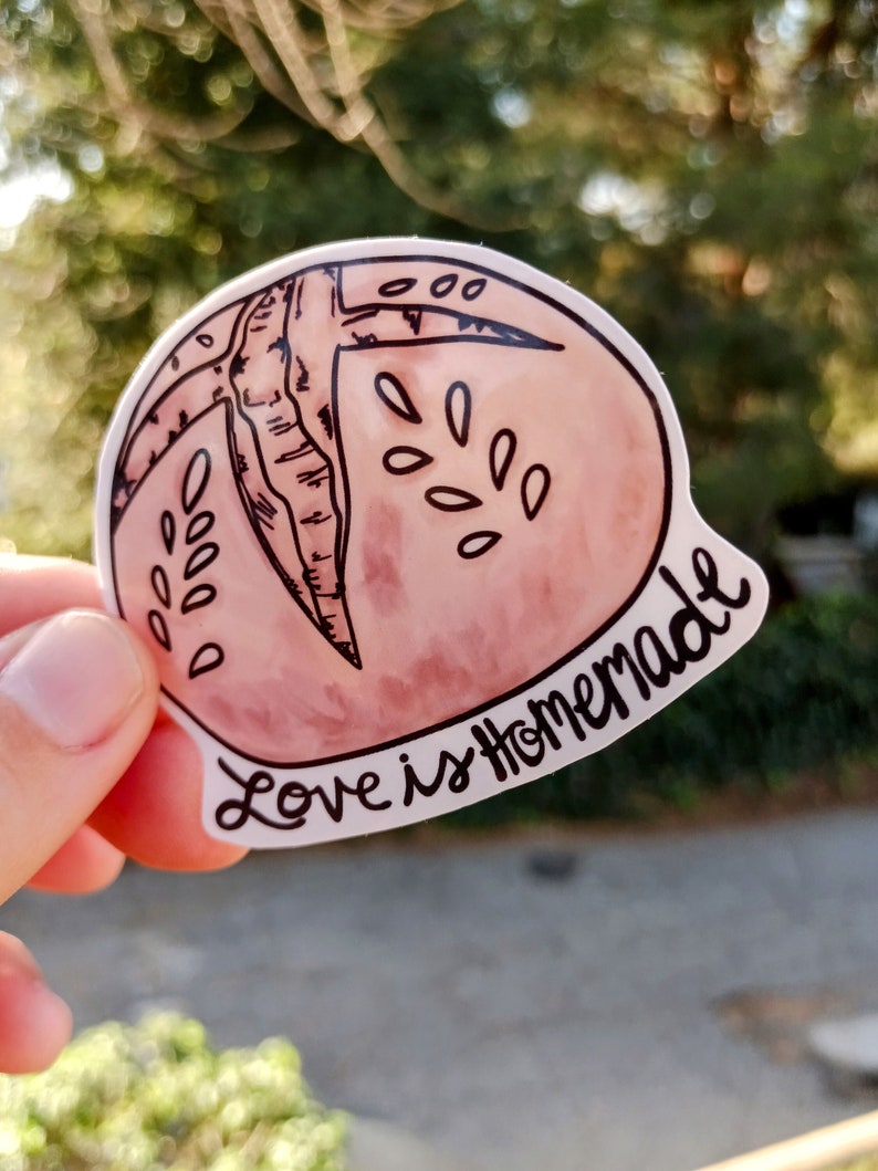 May include: A pink and white sticker with a hand-drawn illustration of a peach and the text "Love is Homemade".