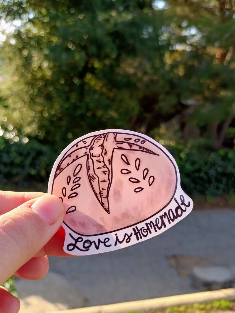 May include: A pink and white sticker with a hand-drawn illustration of a peach and the text "Love is Homemade".