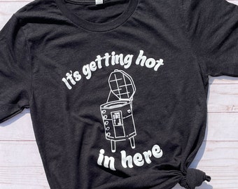 May include: Black t-shirt with white text that reads "It's getting hot in here" and a graphic of a smoker with the lid open.
