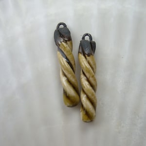 May include: Two twisted bone-like pendants with dark brown tops and a light brown and white swirl pattern.