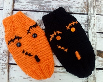 May include: Two knitted Halloween-themed pet sweaters. One is bright orange with black stitched details and black button eyes. The other is black with orange stitched details and orange gem eyes. Both have a pumpkin shape.